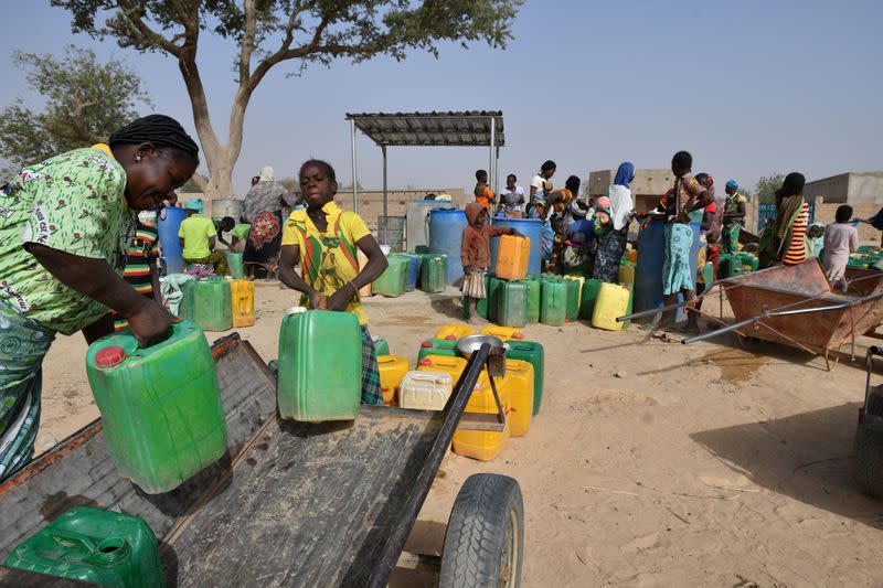 Displaced people, who fled from attacks of armed militants in town of Roffenaga, carry their jerrycans at the water point near UNHCR camp in Pissila