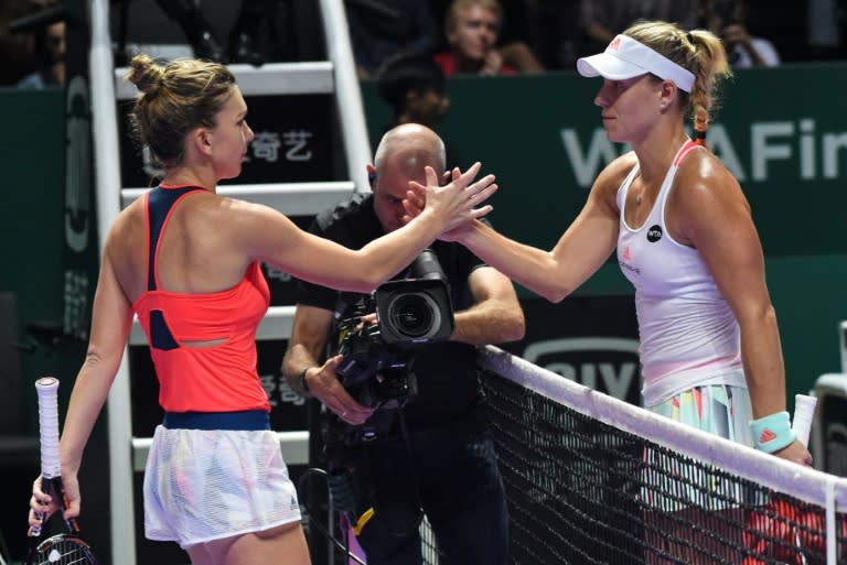 German's Angelique Kerber (R) shakes hands with Romania's Simona Halep (L) followinh their women's singles match during the WTA finals tennis tournament in Singapore on October 25, 2016