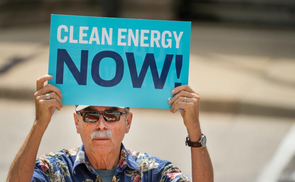 Charlie Bensinger holds up a sign during a protest against We Energies' plans to delay the closing of the power plant in Oak Creek.