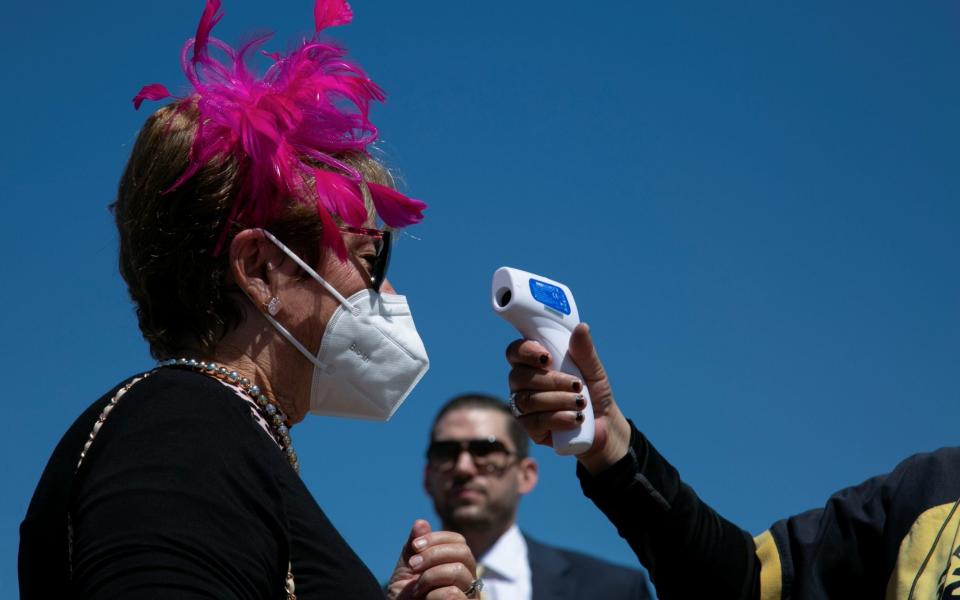 Security checks people's temperature at the entrance of Churchill Downs in the day of the 147th Oaks, the day before Kentucky Derby in Louisville, Kentucky - AMIRA KARAOUD/REUTERS