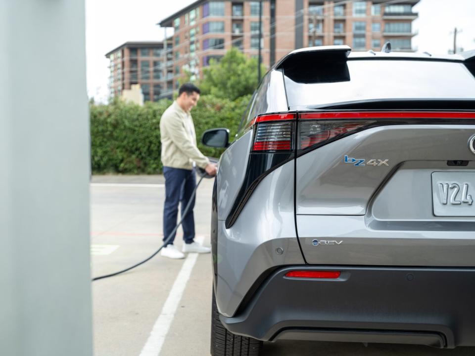 A person plugging a charger into a Toyota bZ4X electric SUV. 