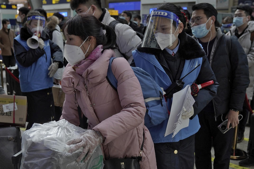 Workers wearing face masks and face shields to help curb the spread of the coronavirus assist masked passengers to board their trains at the South Train Station in Beijing, Thursday, Jan. 28, 2021. Efforts to dissuade Chinese from traveling for Lunar New Year appeared to be working. Beijing's main train station was largely quiet on the first day of the travel rush and estimates of passenger totals were smaller than in past years. (AP Photo/Andy Wong)