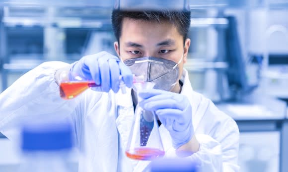 Scientist mixing two flasks.