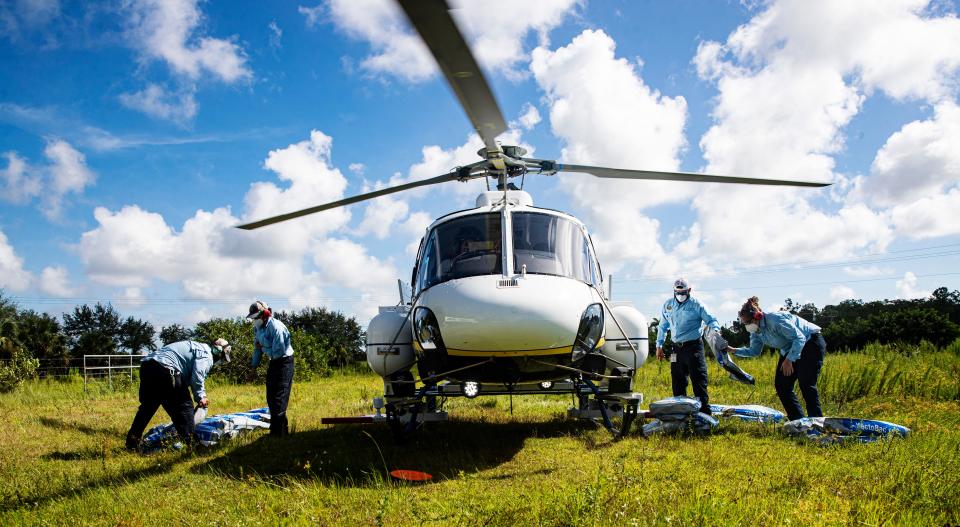 From left, Lee County Mosquito Control employees, Nelson Aviles, Johan Elrubaie, Julio Ledezma and Anne Askew fill a helicopter with mosquito larvicide off of Corkscrew Road on Wednesday, August 31, 2022. The crew was treating for mosquito larvae in the area.  