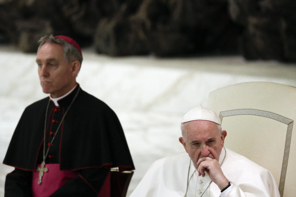 FILE - In this Friday, March 22, 2019 file photo, Pope Francis, flanked by Monsignor Georg Gaenswein, listens to a faithful's speech on the occasion of an audience in the Paul VI hall at the Vatican. The Vatican press office denied Wednesday Feb. 5, 2020 that Gaenswein had been suspended as head of the papal household following his role in a controversial book on priestly celibacy co-written by Emeritus Pope Benedict XVI. It said his absence from Pope Francis’ private and public audiences for the past several weeks was “due to an ordinary redistribution of the various commitments and duties of the prefect.” (AP Photo/Gregorio Borgia, file)
