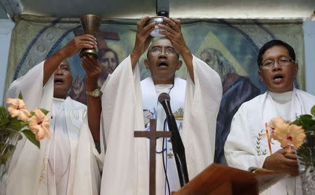 Roman Catholic priest Father Jess Siva (C) leads a Holy Mass next to fellow priests Father Elmer Cajilig (L) and Father Hector Canto (R) at a chapel in Lambunao, Iloilo on Panay island in central Philippines January 11, 2015. REUTERS/Erik De Castro