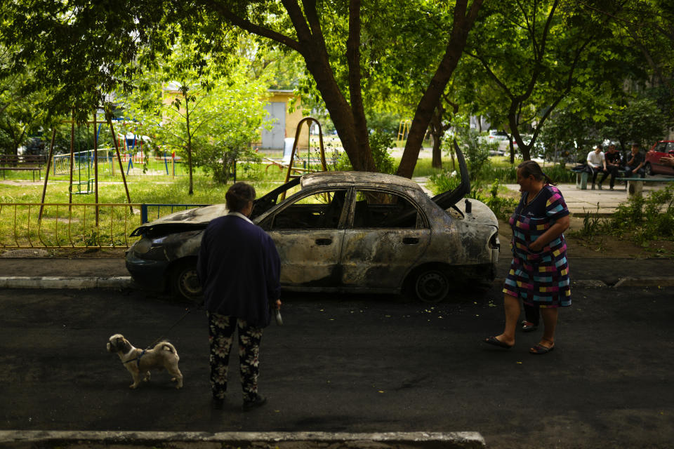 Local residents look at a car burned by a bombing earlier in the day in Mykolaiv, Ukraine, Monday, May 16, 2022. (AP Photo/Francisco Seco)