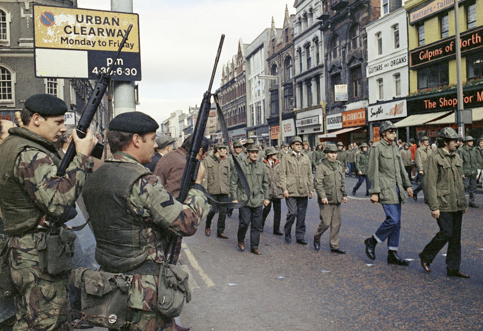 FILE - In this Aug. 1972 file photo British troops watch as members of the Ulster Defence Association parade through Belfast, Northern Ireland. The chaotic scenes during a week of violence on the streets of Northern Ireland have stirred memories of decades of Catholic-Protestant conflict, known as "The Troubles." A 1998 peace deal ended large-scale violence but did not resolve Northern Ireland's deep-rooted tensions. (AP Photo, File)