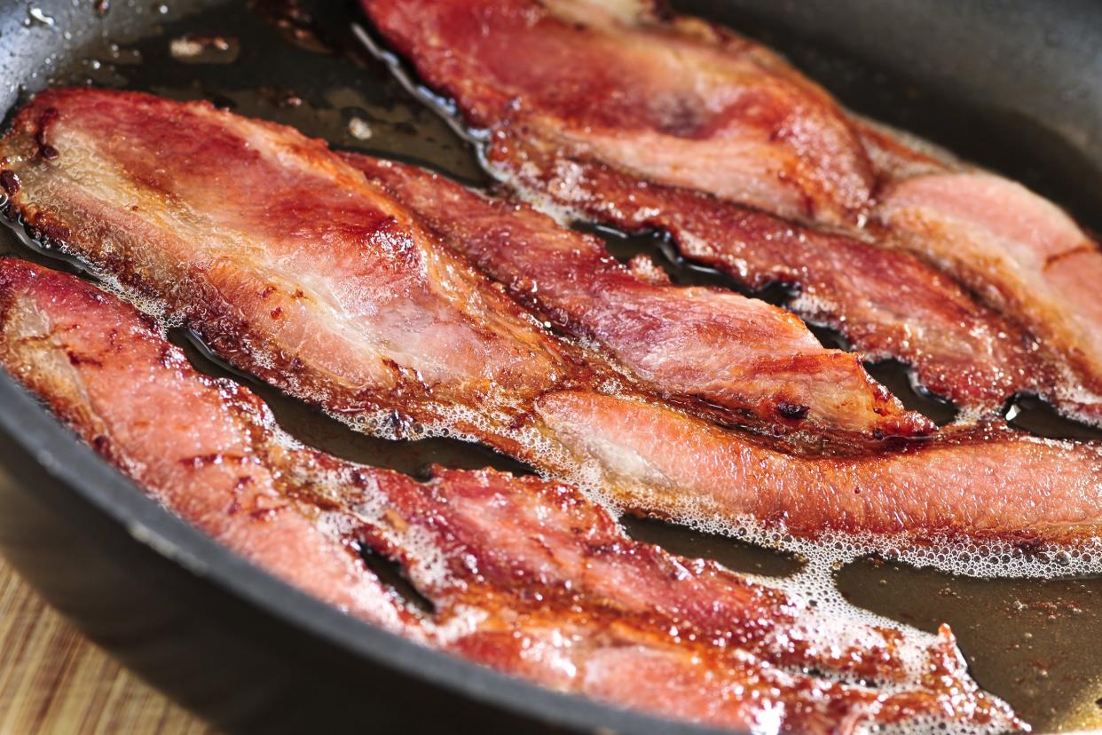 bacon strips sizzling on a frying pan