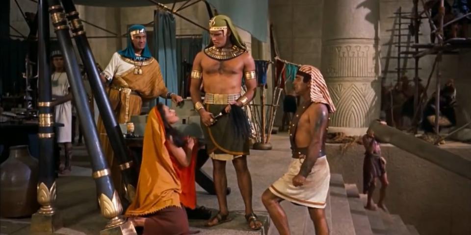 A woman is on her knees begging a man dressed as an Egyptian holding a whip.