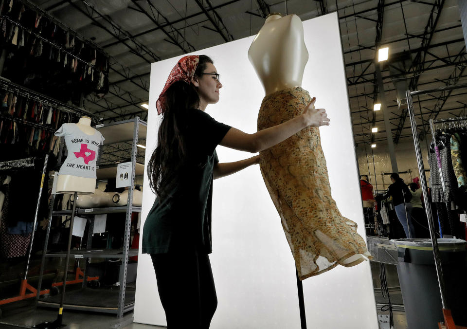 FILE - In this March 12, 2019, file photo, Samantha Estes prepares garments to be photographed at the ThredUp sorting facility in Phoenix. J.C. Penney and Macy’s are in the midst of rolling out a few dozen ThredUp branded shops each in time for the back-to-school shopping season. The partnerships follow a similar deal with department store retailer Stage Stores. (AP Photo/Matt York, File)