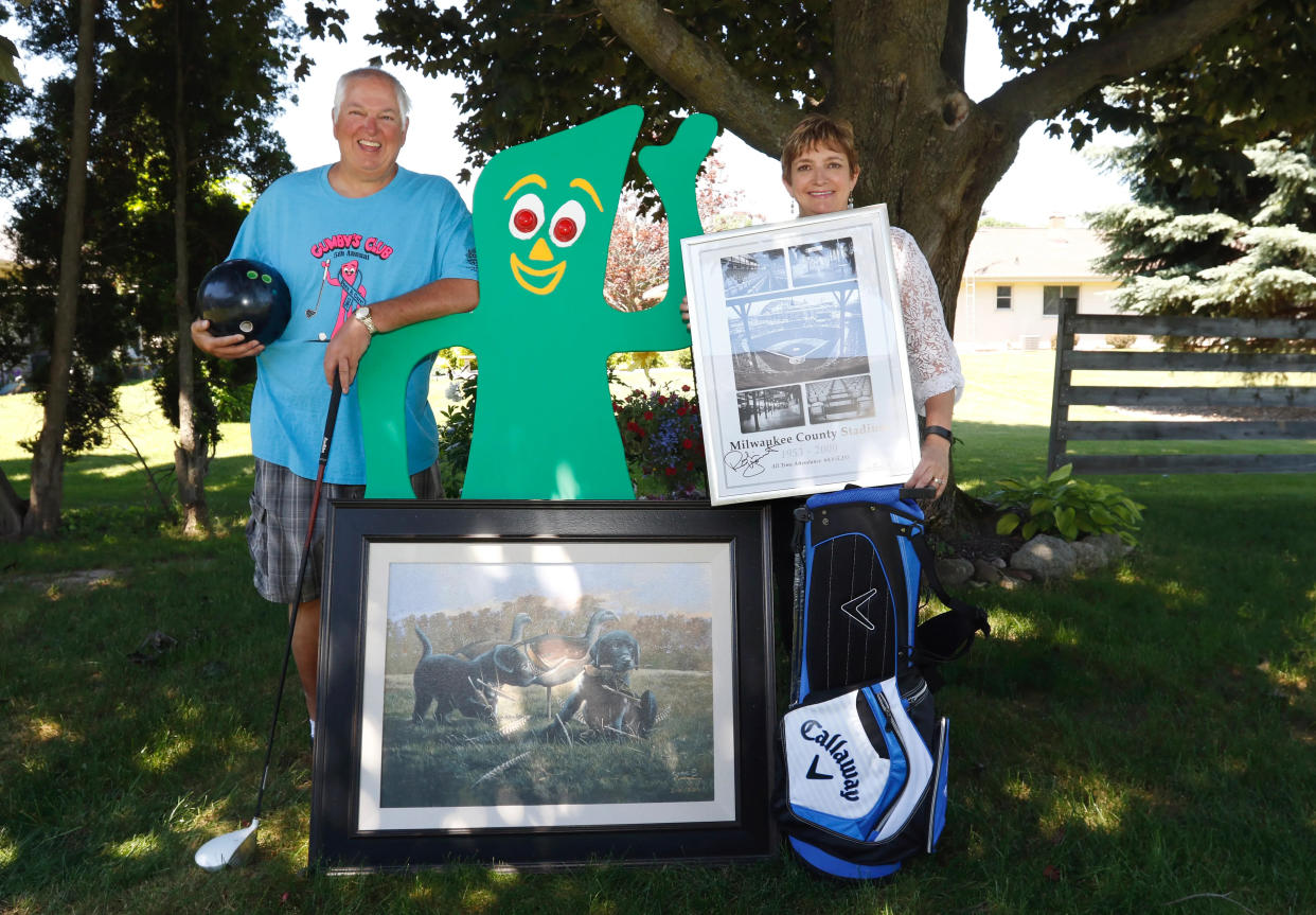 FILE - Rob 'Gumby' and Denise Roseff pose with a wooden Gumby board and the prizes for the sixth annual Gumby's Club fundraiser in their back yard in June 2016. Gumby's Club Fore A Cure is an annual fundraiser the Roseffs host to raise money to help local families affected by cancer.