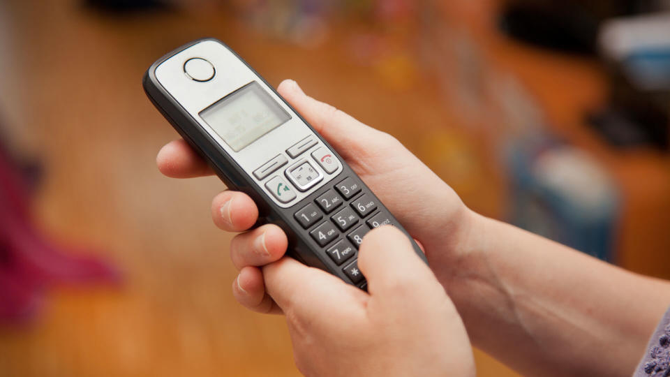 woman typing number into phone at home - Image.