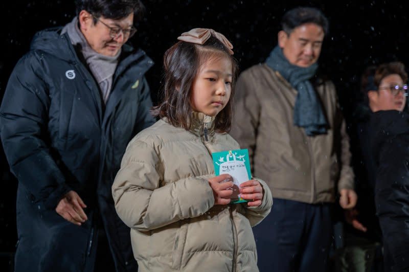 A girl holds a message of peace at a ceremony Saturday night at Aegibong Peace Ecopark in Gimpo, South Korea. Photo by Thomas Maresca/UPI