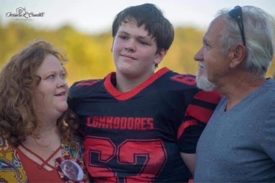 Aaron "Mick" Crawford is seen with his parents, Ronda and David Crawford, in his football jersey. Mick was the youngest of eight siblings.