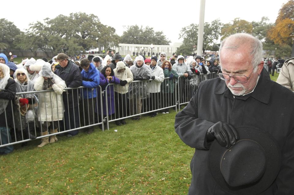 A man bows his head as spectators gather in Dealey Plaza during ceremonies marking the 50th anniversary of JFK's assassination in Dallas