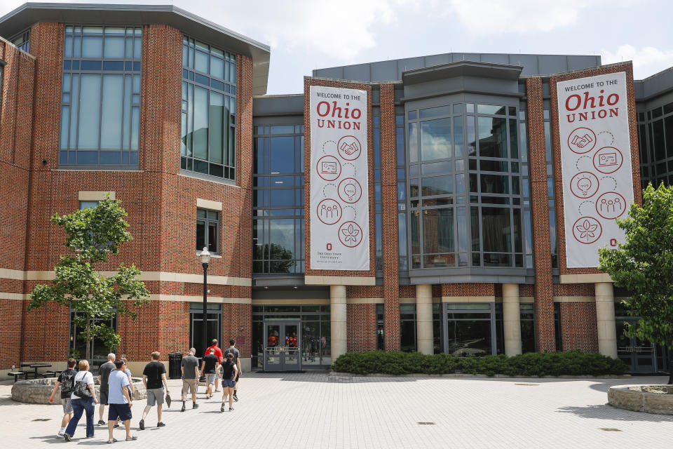 FILE - In this May 18, 2019 file photo pedestrians walk up to the The Ohio State University's student union in Columbus, Ohio. Mike Drake, the president of The Ohio State University says he'll retire from that role next year. Drake's five-year tenure at one of the nation's largest universities has included strategic successes, such as record numbers for the school in applications, graduates, research expenditures and donor support. But it also has been marred by scandals involving the university's marching band, a prominent football coach and a former team doctor accused of widespread sexual abuse. (AP Photo/John Minchillo, File)