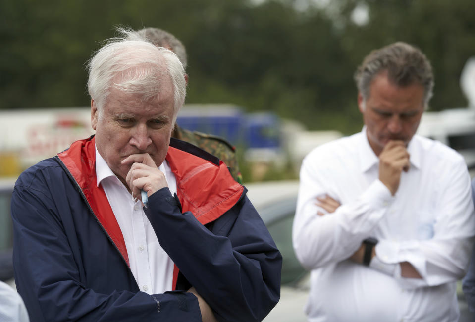 Federal Minister of the Interior Horst Seehofer, left, gives a press statement during a visit to the Federal Agency for Technical Relief (THW), which is on flood duty there in Bad Neuenahr, Germany, Monday, July 19, 2021. (Thomas Frey/dpa via AP)
