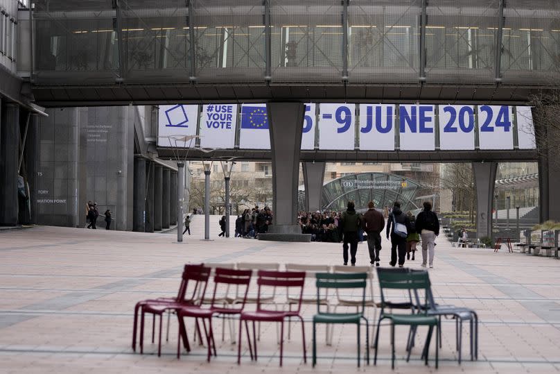 People gather in front of a banner advertising the European elections outside the European Parliament in Brussels, January 2024