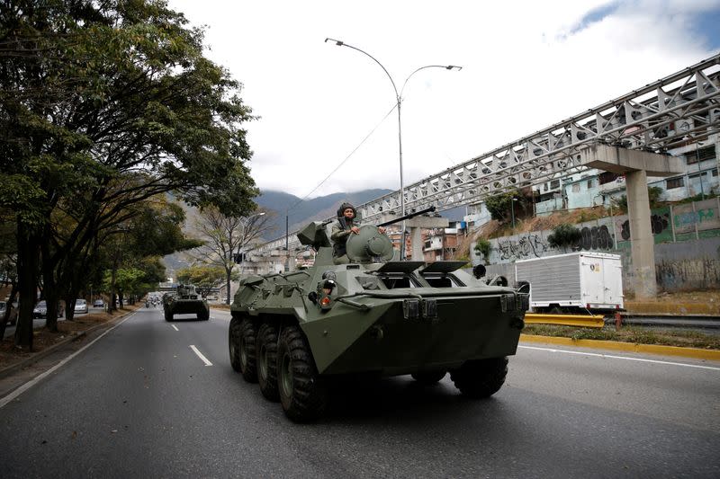 A soldier is seen over an armored vehicle driven along a highway during a military exercise in Caracas