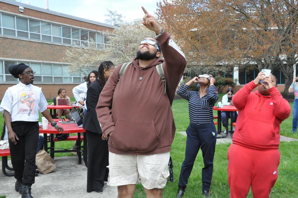 Deyvon Ross points toward the sun and moon while watching the eclipse at Delaware State University in Dover April 8, 2024.