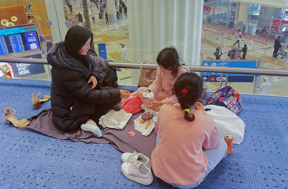 A woman and her daughters eat as they wait for their flight (REUTERS)