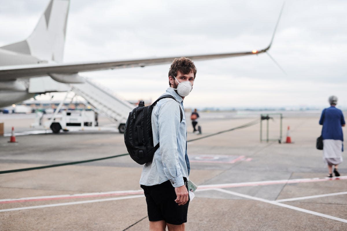 A person wearing a mask boards a plane.