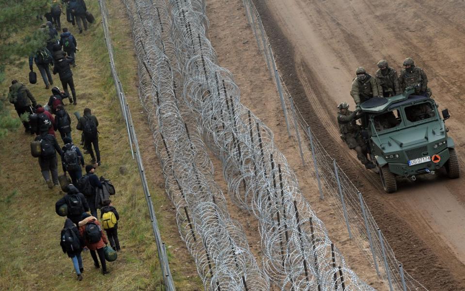 A barbed wire fence separates migrants on the Belarusan side of the border from entering Poland