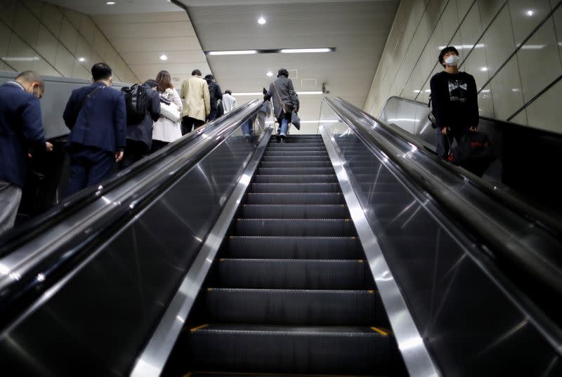 Passengers wearing protective face masks, following an outbreak of the coronavirus disease, walk to work the day before a state of emergency is expected to be imposed at a station in Tokyo