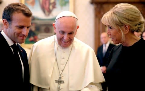 Pope Francis (C) smiles next to French President Emmanuel Macron (L) and his wife Brigitte as they exchange gifts at the end of a private audience at the Vatican  - Credit: ALESSANDRA TARANTINO/AFP
