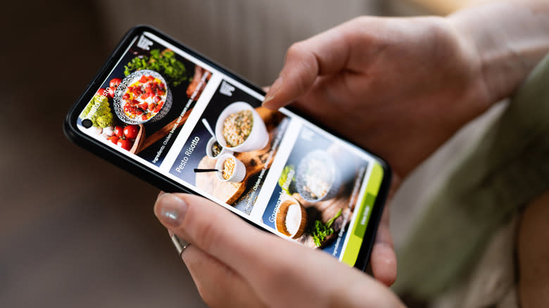 Hands holding phone with online restaurant menu