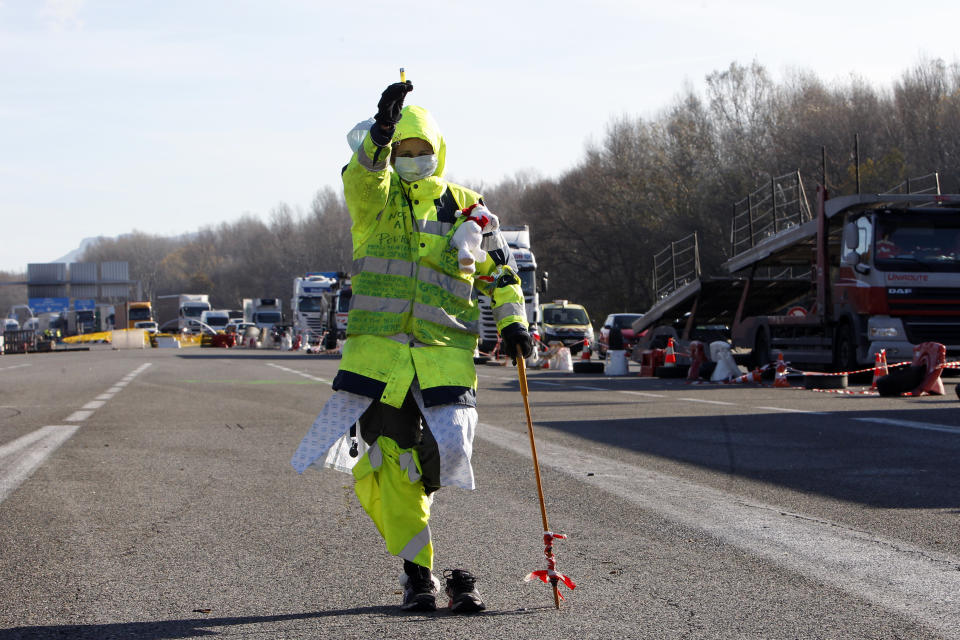 A demonstrator wearing a yellow vest painfully walks on a motorway as protesters open the toll gates near Aix-en-Provence, southeastern France, Tuesday, Dec. 4, 2018. French Prime Minister Edouard Philippe announced a suspension of fuel tax hikes Tuesday, a major U-turn in an effort to appease a protest movement that has radicalized and plunged Paris into chaos last weekend. (AP Photo/Claude Paris)