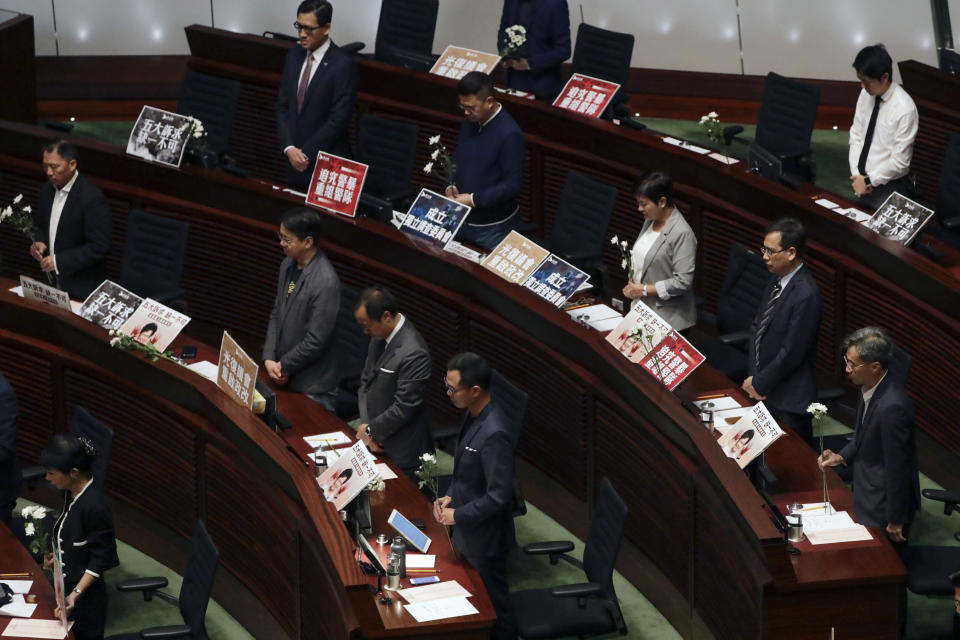 Pro-democracy lawmakers, some holding flowers, perform a silent prayer with protest plate card during a question and answer session with Hong Kong Chief Executive Carrie Lam at the chamber of the Legislative Council in Hong Kong, Thursday, Oct. 17, 2019. (AP Photo/Mark Schiefelbein)