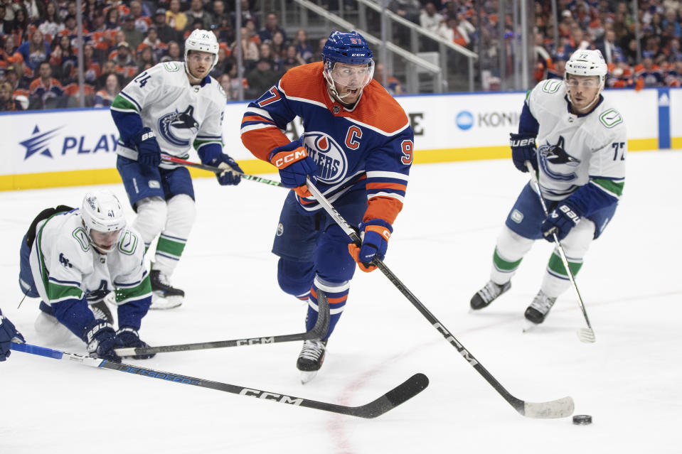 Vancouver Canucks players chase Edmonton Oilers' Connor McDavid (97) during the second period of an NHL hockey game in Edmonton, Alberta, Saturday, Oct. 14, 2023. (Jason Franson/The Canadian Press via AP)