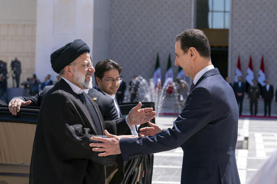 In this photo released by the official Facebook page of the Syrian Presidency, Syrian President Bashar Assad, right, welcomes Iranian President Ebrahim Raisi in Damascus, Syria, Wednesday, May 3, 2023. Iranian President Raisi Wednesday met Syrian President Assad in Damascus in a bid to boost cooperation between the two allies, state media reported. (Syrian Presidency via Facebook via AP)