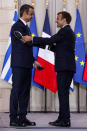 Greek Prime Minister Kyriakos Mitsotakis, left, and French President Emmanuel Macron shake hands after the signing of a new defense deal at The Elysee Palace Tuesday, Sept. 28, 2021 in Paris. France and Greece announced on Tuesday a major, multibillion-euro defense deal including Athens' decision to buy three French warships. (Ludovic Marin, Pool Photo via AP)