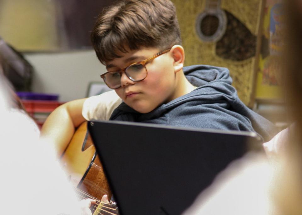 Simon Flores, an 8th grader at Salina South Middle School, strums his guitar during a warm-up in advanced guitar class.