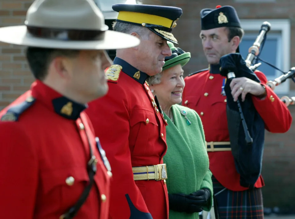 Queen Elizabeth II is escorted by Royal Canadian Mounted Police Commissioner Giuliano Zaccardelli (C) during her visit to 'N' Division in Ottawa, October 14, 2002. The Queen visited the RCMP facility on the last day of her 11-day Golden Jubilee tour of Canada. REUTERS/Andy Clark AC
