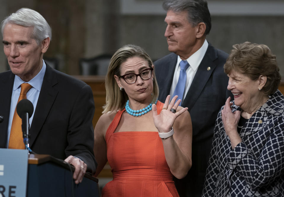 FILE- Sen. Kyrsten Sinema, D-Ariz., center, gestures during a news conference at the Capitol in Washington, Wednesday, July 28, 2021, while working on a bipartisan infrastructure bill with, from left, Sen. Rob Portman, R-Ohio, Sen. Joe Manchin, D-W.Va., and Sen. Jeanne Shaheen, D-N.H. Though elected as a Democratic, Sinema announced Friday, Dec. 9, that she has registered as an independent, but she does not plan to caucus with Republicans, ensuring Democrats will retain their narrow majority in the Senate. (AP Photo/J. Scott Applewhite, File)