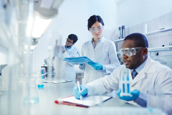 Scientists collaborating together at a table inside a lab.