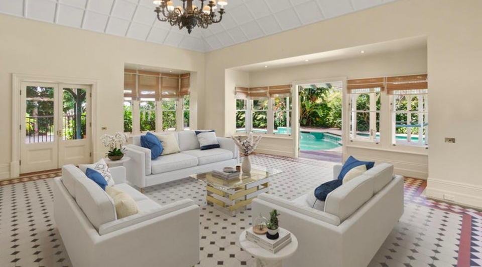 A living room with white couches overlooking a resort style pool.