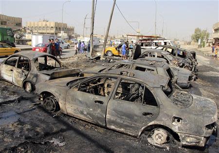 People stand at the site of a car bomb attack in Baghdad's al-Shaab district, October 27, 2013. REUTERS/Thaier Al-Sudani