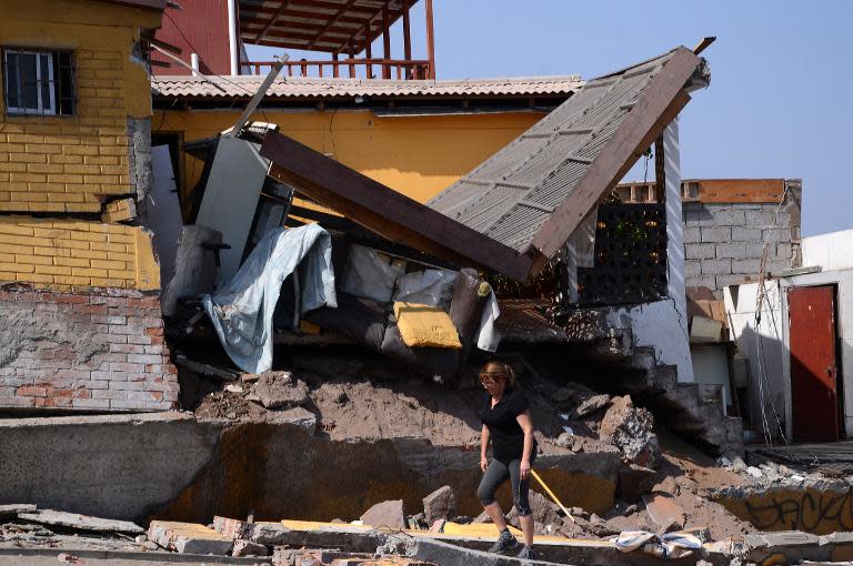 A woman walks next to a destroyed house in Iquique, northern Chile, on April 2, 2014 a day after a powerful 8.2-magnitude earthquake hit off Chile's Pacific coast