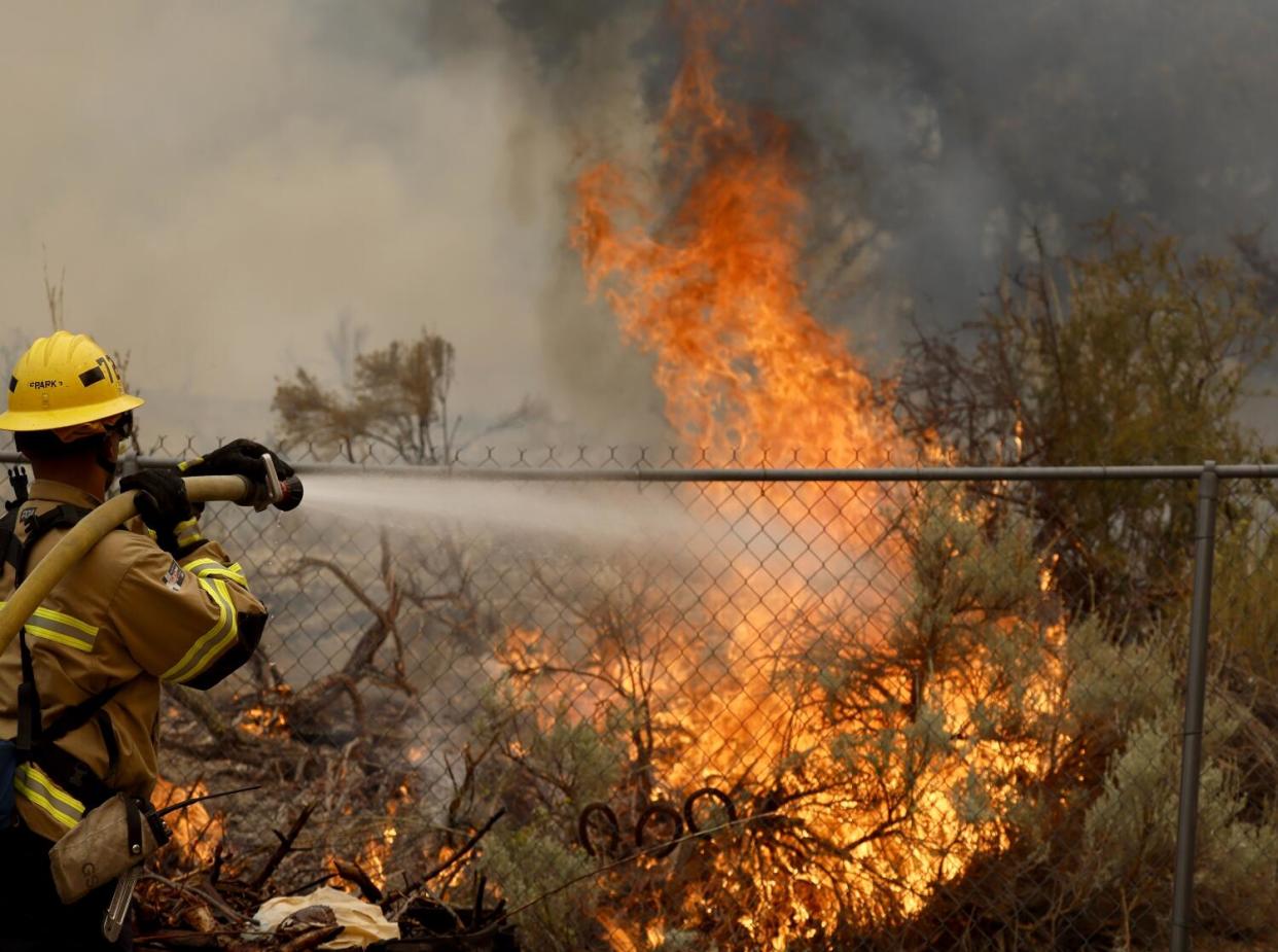 San Bernardino County firefighters work to save a home from the Bridge fire burning in Wrightwood.