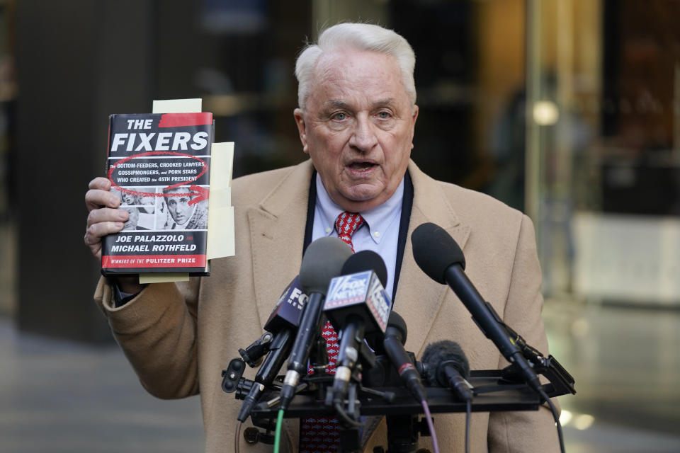 Attorney Bob Costello holds up a book while talking to reporters after testifying before a grand jury investigating Donald Trump in New York, Monday, March 20, 2023. (AP Photo/Seth Wenig)