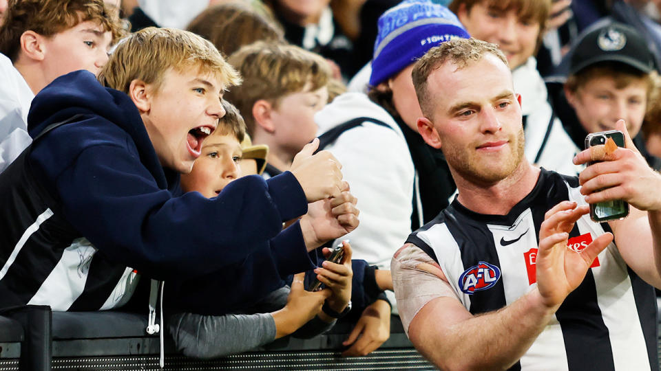 Collingwood player Tom Mitchell takes a photo with a fan.