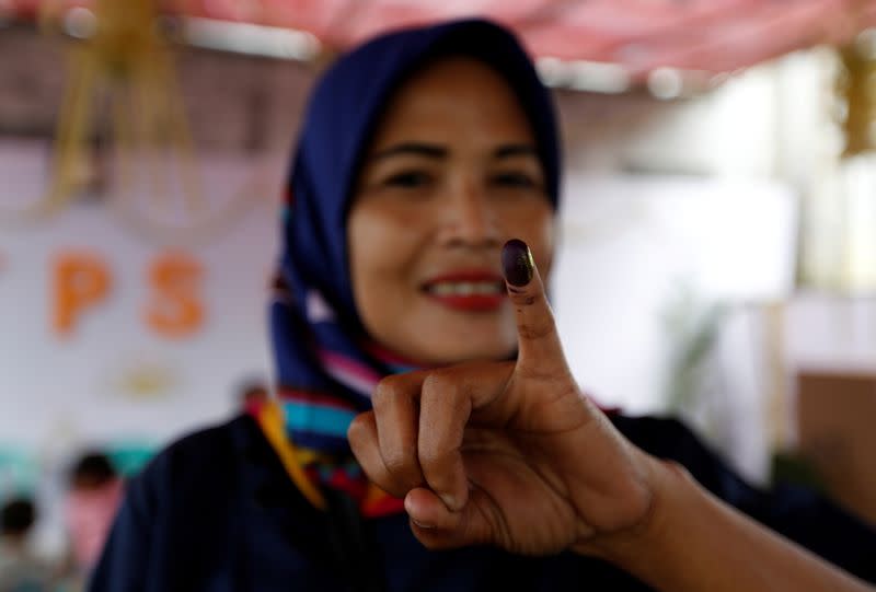 FILE PHOTO: An Indonesian woman shows her ink-stained finger after casting her vote during regional elections in Tangerang