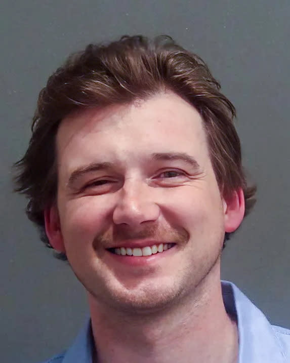 Morgan Wallen smiling in 2024 mugshot in blue button-down shirt