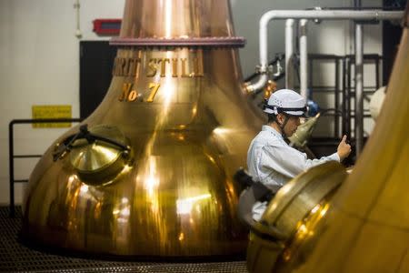 A worker takes a sample from a spirit still at Suntory Holdings' Yamazaki Distillery in Shimamoto town, Osaka prefecture, near Kyoto, December 1, 2014. REUTERS/Thomas Peter