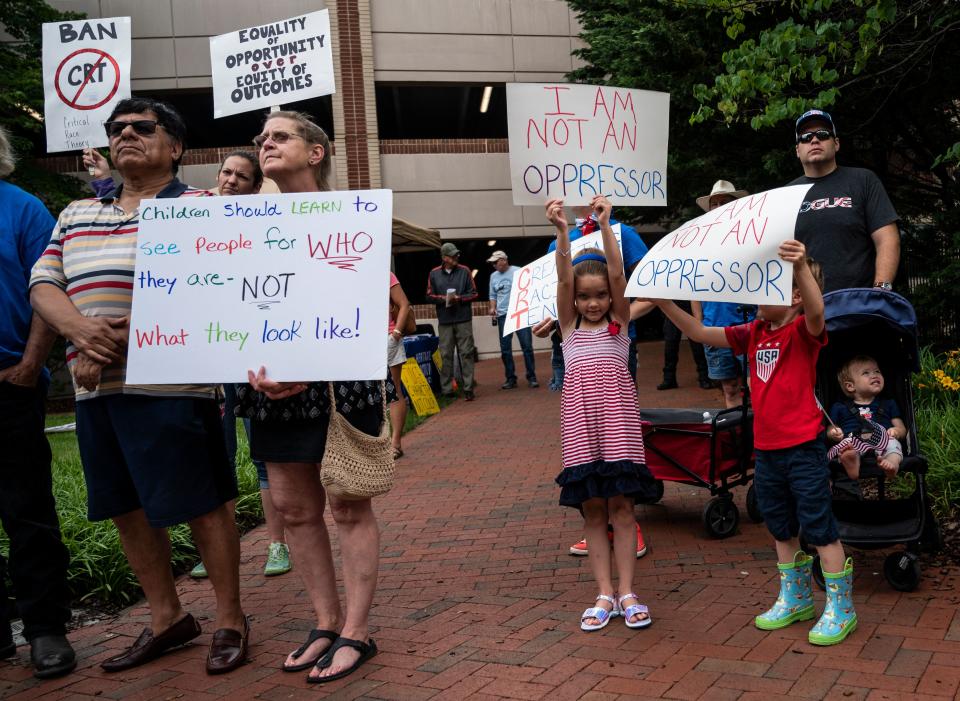 A group of people hold signs reading I am not an oppressor, and Children should learn to see people for who they are — not what they look like.